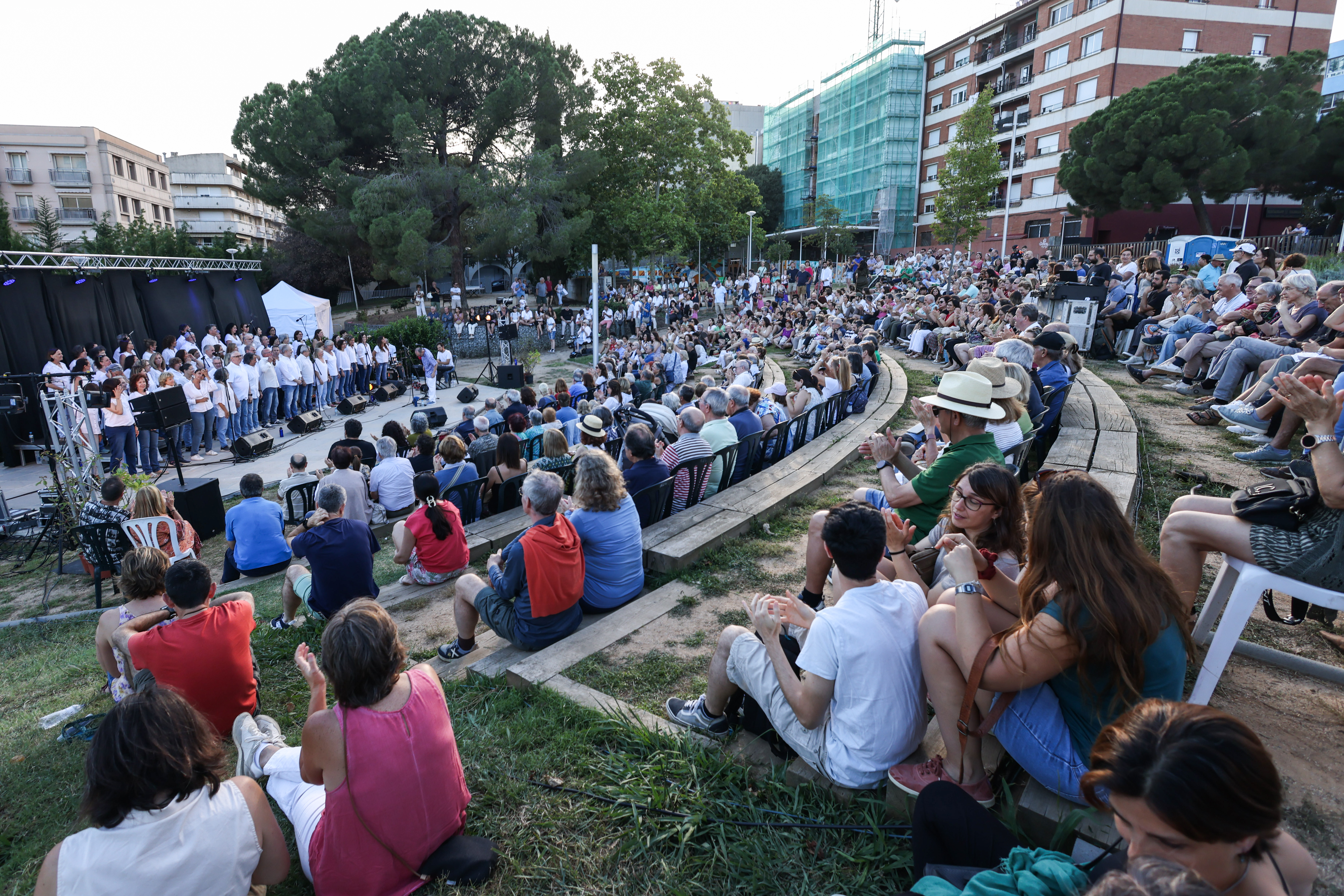 Públic assegut d'esquena en un uns jardins en forma d'amfiteatre